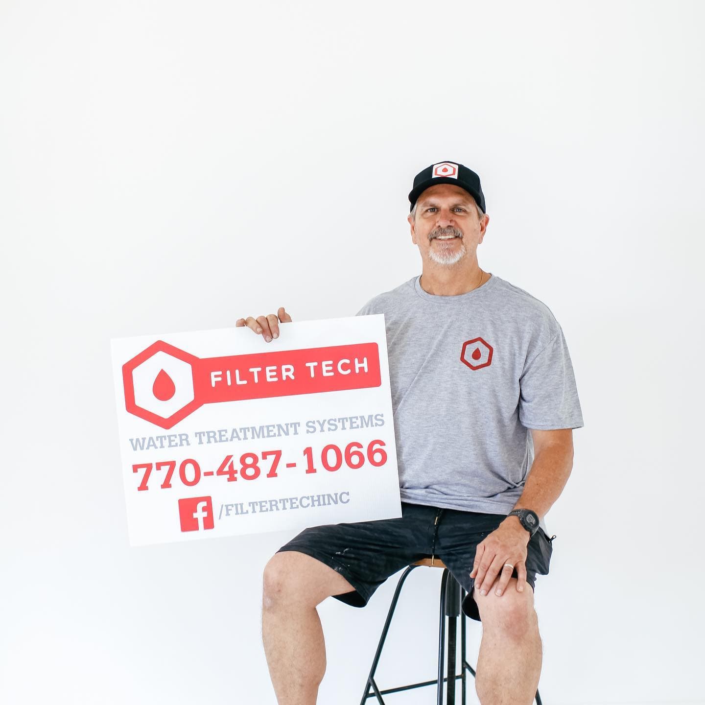 Jay Hanlon holding a Filter Tech sign with the company phone number