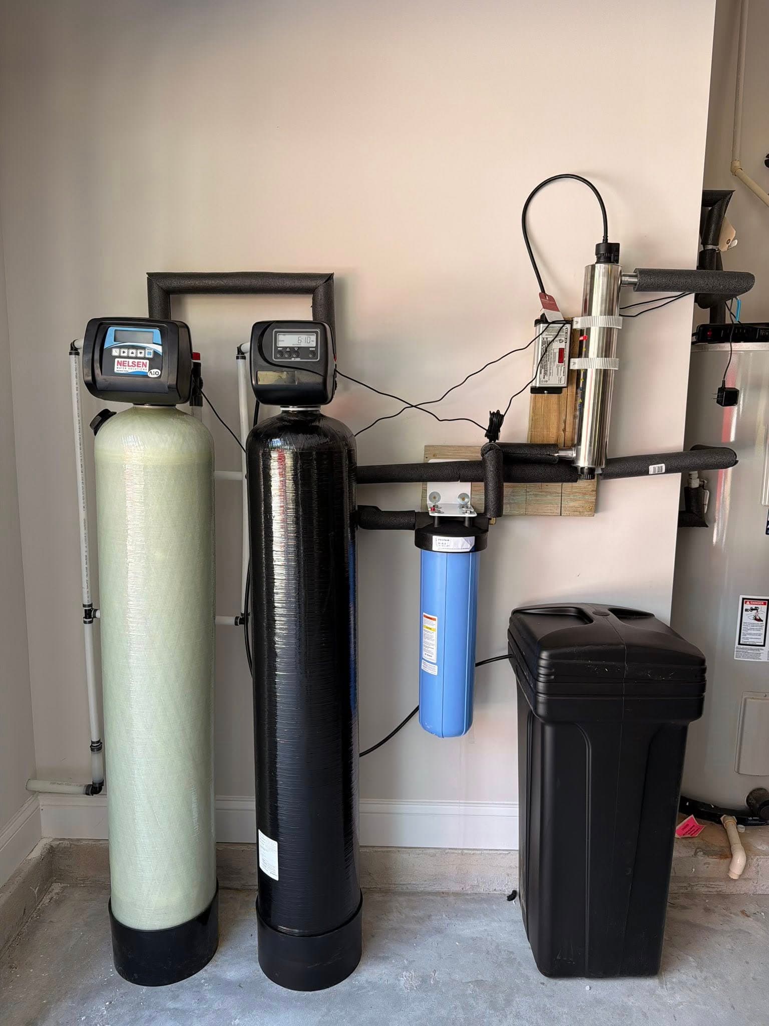 Finished whole-house filtration installation with twin tanks, brine reservoir, and UV light